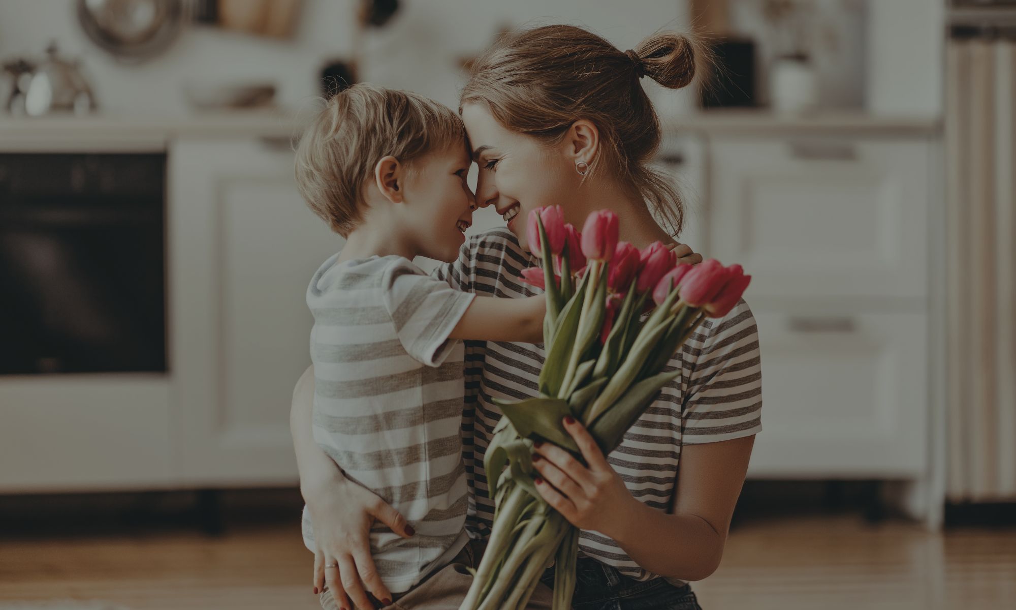 mãe com filho pequeno no colo e buquê de tulipas, simbolizando a culpa materna e o relacionamento entre a mãe e os filhos.